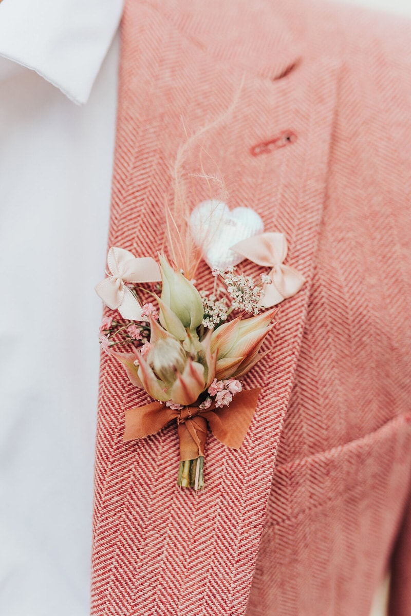 Romantic Boho Desert Pastel Wedding Ideas | Coral pink wedding suit for the groom featuring a bold chevron pattern and a blushing bride boutonniere tied with terracotta ribbon. | Photography: Rebecca Carpenter via The Stars Inside