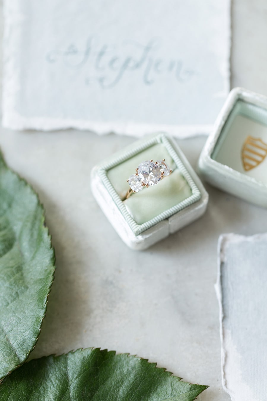 Yellow gold oval diamond trilogy engagement ring displayed in green velvet ring box | Photography: Camille Catherine Photography via Elizabeth Anne Designs