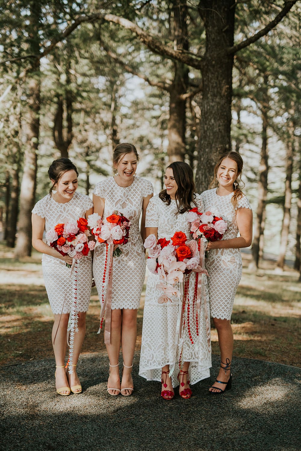 Modern Red & Pink Wedding Ideas | White lace bride and bridesmaid dresses paired with pink and red bouquets featuring roses, orchids and trailing ribbons | Photography: Alana Taylor Photography via Hello May