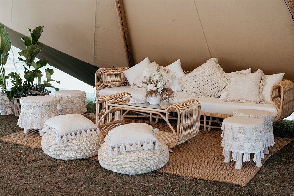 Outdoor Festival Bohemian Wedding Inspiration | ealight holders and fresh blooms in white vases. Potted plants in wicker baskets add lush greenery to this cool space. | Photography: Shae Estella Photo