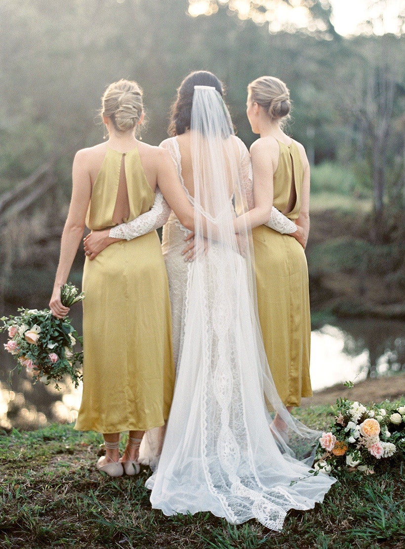 Vintage boho bride wearing long sleeved lace wedding dress with cathedral veil, alongside bridesmaids wearing silk chartreuse yellow dresses | Byron Loves Fawn