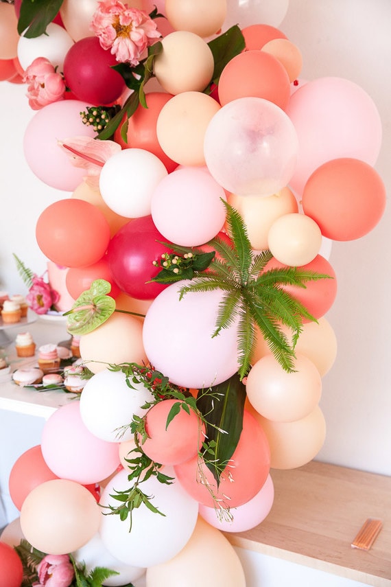 Coral, pink and peach balloon installation for dessert table featuring tropical plants | Kayla Plouffe via 100 Layer Cakelet