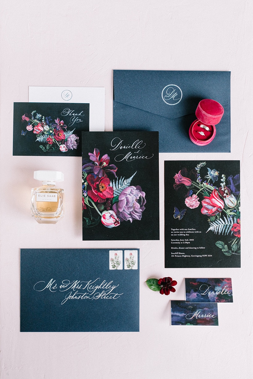 Jewel toned wedding invitation stationery flat lay with floral illustration, navy envelopes, perfume bottle and velvet ring box | Nattnee Photography